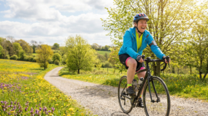 Woman cycling along a scenic countryside path surrounded by spring wildflowers