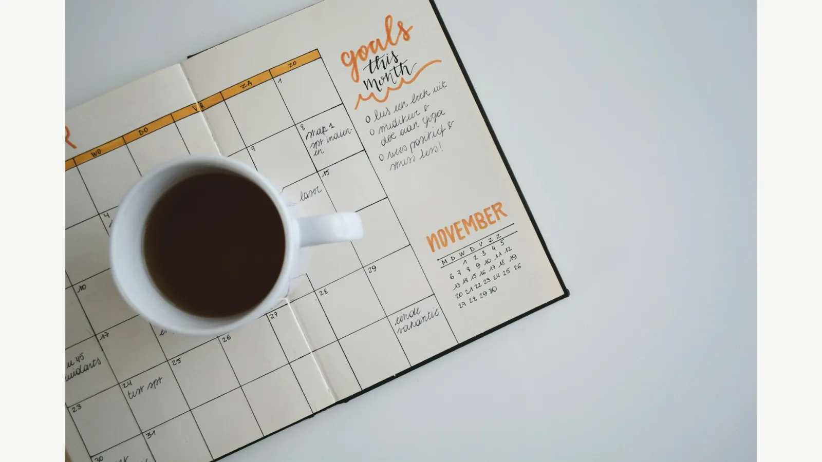 A planner and coffee cup on a table.