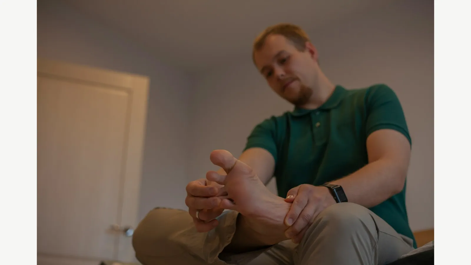 A seated adult holding and inspecting a foot.