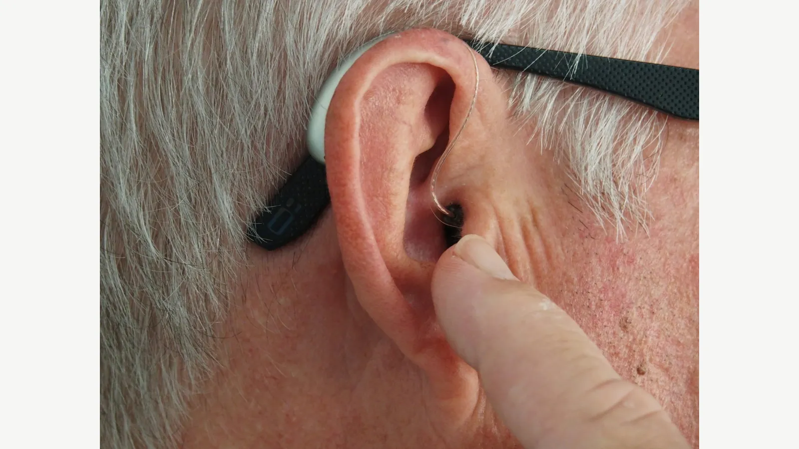 A close-up of a hearing aid worn behind an ear.