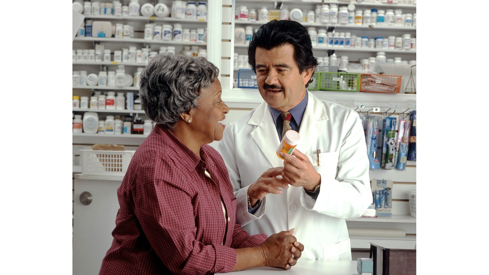 A pharmacist discusses a prescription with a woman at a pharmacy counter.